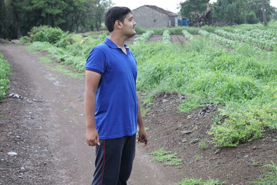 Young man looking away while standing on land