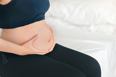 Young pregnant woman touching her belly, she holding baby in pregnant belly, early pregnancy