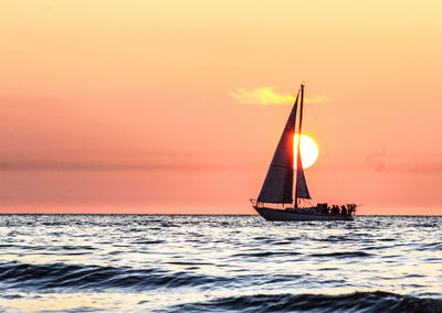 Sailboat sailing on sea against sky during sunset