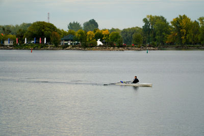 Man rowing boat in water against sky