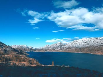 Scenic view of sea and mountains against blue sky