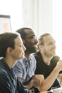 Smiling male and female business people listening in meeting at creative office