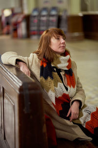 Thoughtful woman looking away while sitting on bench