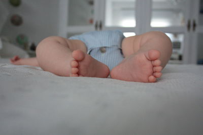 Low section of baby sleeping on bed at home