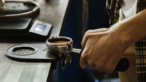 Barista presses ground coffee using tamper. professional barista working makeing coffee 