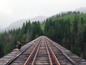 Side view of woman sitting on vance creek viaduct leading towards mountains