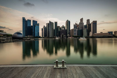 Modern buildings by river against sky in city