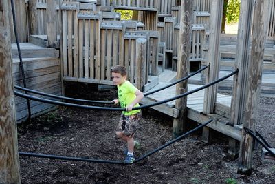 Full length of playful boy on play equipment at park