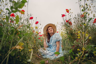 Young woman is sitting on a poppies field