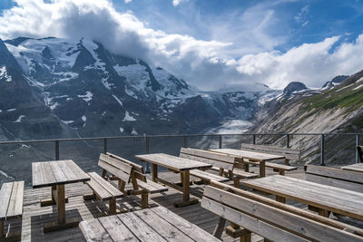 Empty benches on snowcapped mountains against sky