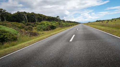 Empty road along landscape and trees against sky