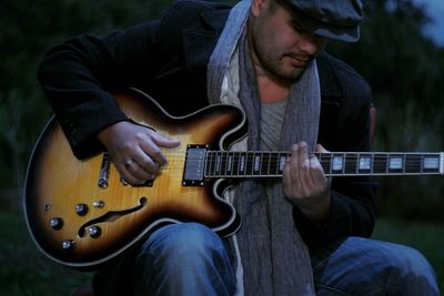 Man playing guitar while sitting outdoors