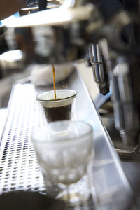 Close up of espresso maker pouring espresso into a small glass in a coffee shop