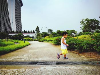 Full length of beautiful woman in park against sky in city