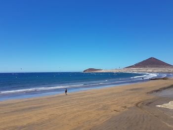 Scenic view of beach against clear blue sky