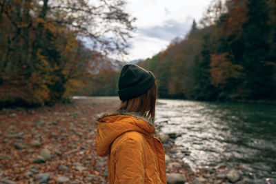 Rear view of man standing by tree during autumn