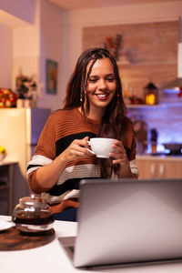 Young woman using mobile phone while sitting on table