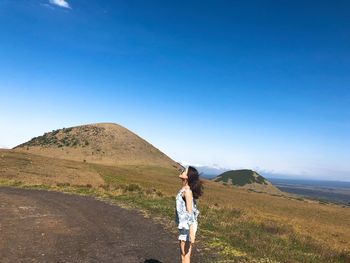 Woman standing on road against blue sky