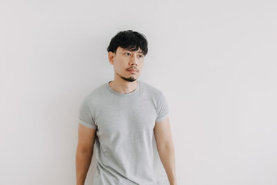 Portrait of young man standing against white background