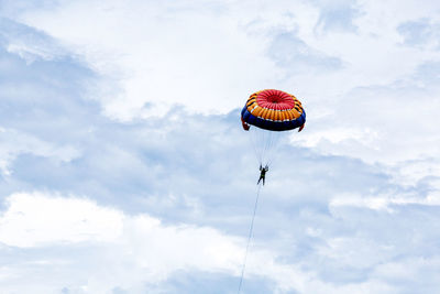 Low angle view of person paragliding against sky