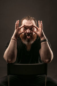 Portrait of man sitting against black background