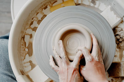 Female hands of potter forming clay product on potters wheel