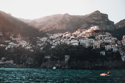 Scenic view of sea by townscape against sky