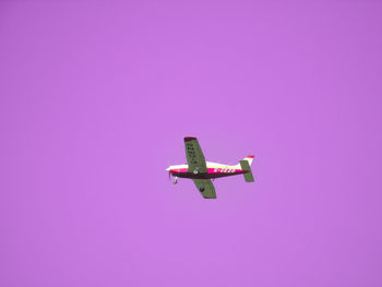 Low angle view of airplane flying against pink sky