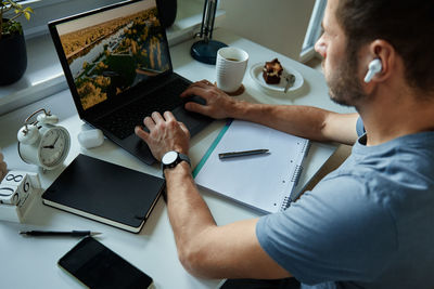 Man sitting at table by the window and using laptop