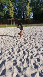 View of boy jumping on sand, teenager doing sports in the park