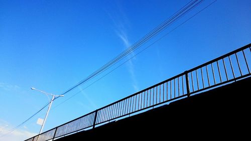 Low angle view of railing against blue sky