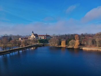 Scenic view of river by buildings against sky