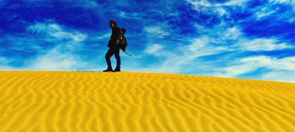Full length of man on sand dune against sky