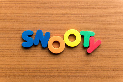 High angle view of colorful snooty text on wooden table