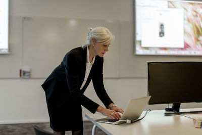 Mature businesswoman using laptop at desk in board room