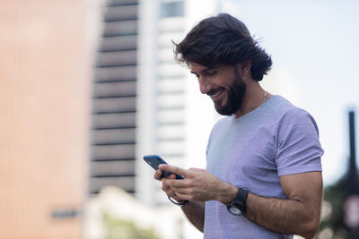 Young man with smartphone at night time with city view  in the background. mobile, technology, urban 