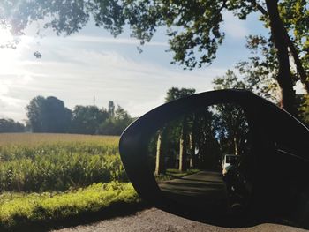 Close-up of side-view mirror against sky