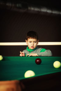 Boy looking at balls on pool table