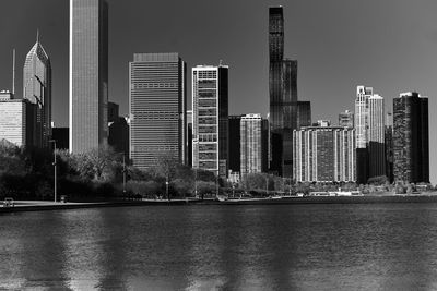 Modern buildings by river against sky in city
