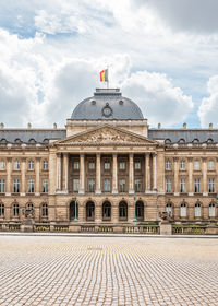 Facade of historical building against cloudy sky