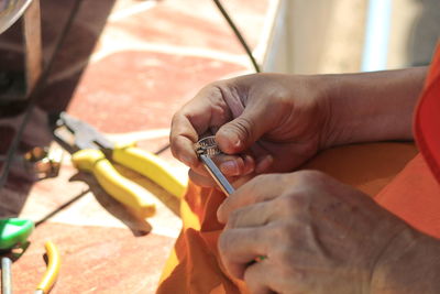 Midsection of worker holding work tools while sitting in workshop