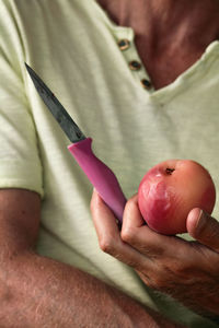 Midsection of man holding poached peach and knife