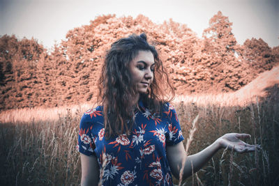 Portrait of young woman standing against plants