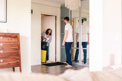 Landlord greeting woman with luggage on doorway in house rental