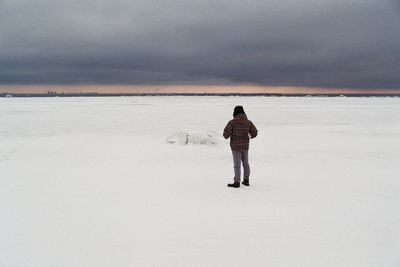 Full length rear view of man standing on beach during winter