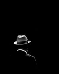 Rear view of man wearing hat standing against black background