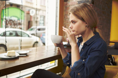 Young woman drinking coffee at cafe