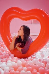 Young woman sitting with red balloons