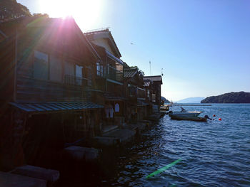 Buildings by sea against clear sky