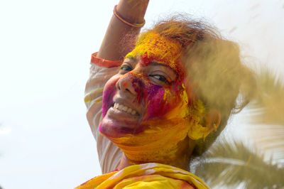 Young indian happy woman with color on face on holi color festival. front view. looking at camera.
